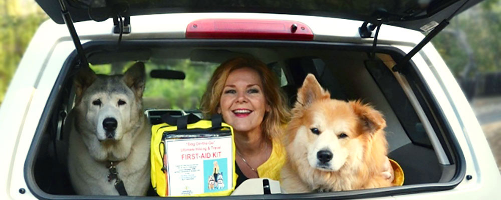 Denise Fleck with her two dogs and a pet first aid kit in car trunk