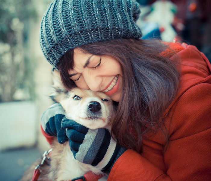 woman in winter gear hugging dog with look of relief