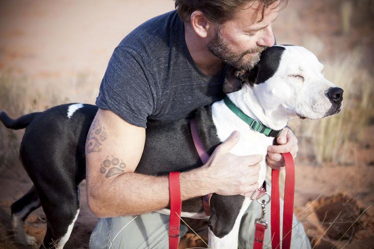 Man loving on his black and white dog outside